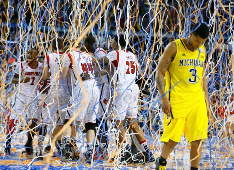 Michigan Burke walks off the court as Louisville celebrates defeating Michigan to win the NCAA men's Final Four championship basketball game in Atlanta